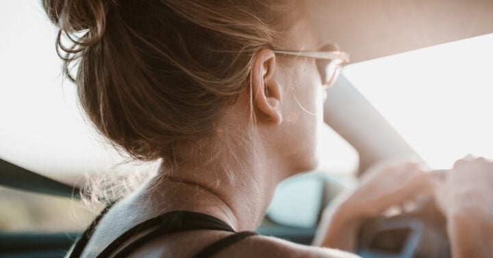 woman with bun in hair holding onto steering wheel