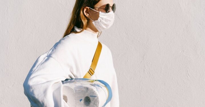 woman with face mask and sunglasses holding toilet paper