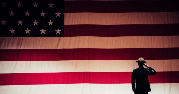 silhouette of military member saluting a large American flag