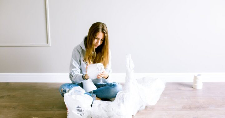 Young girl sitting on the floor fixing a light fixture.