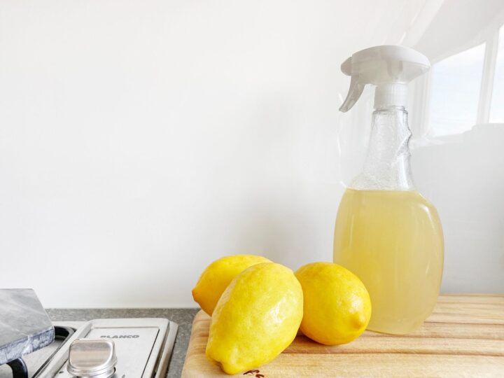 Lemon cleaning spray bottle on kitchen counter next to lemon.