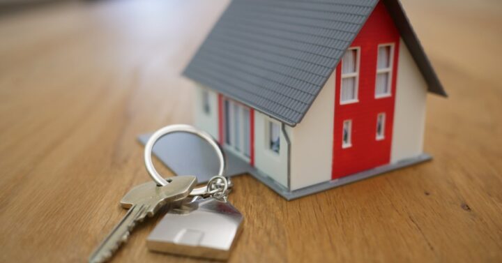 a tiny house keychain attached to a single silver key on a wooden table.