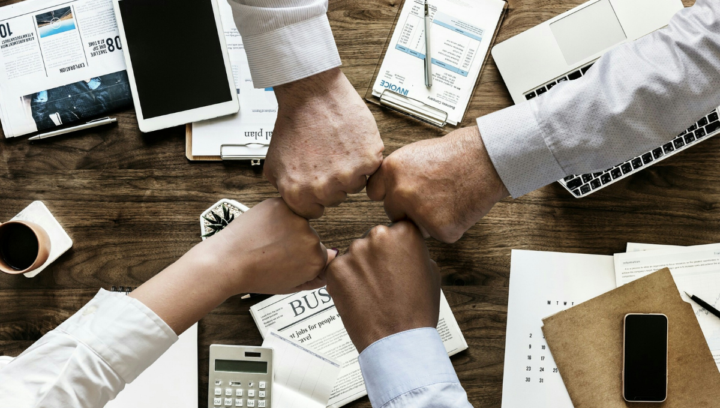 Corporate office workers pounding fists to imply teamwork