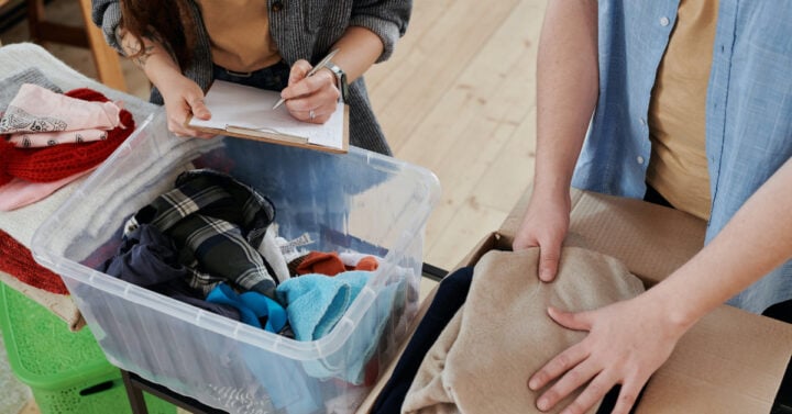 a couple folding clothes and putting them in a storage tub