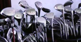 A line of golf clubs packed into bags.