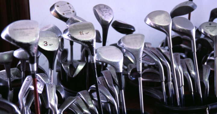 A line of golf clubs packed into bags.