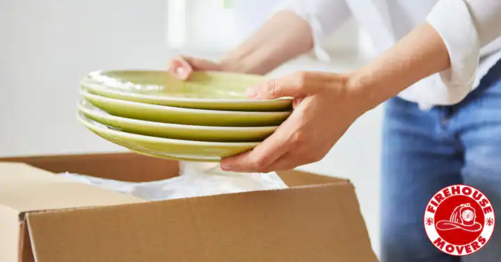 A person carefully unpacking ceramic dishes from a moving box in their new kitchen, featured in a guide on how to find affordable movers.