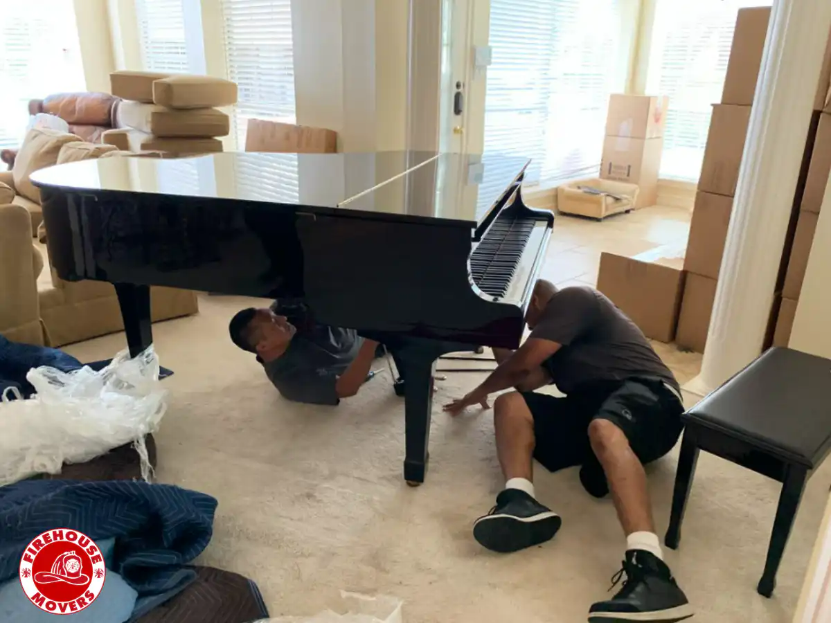 Professional movers from Firehouse Movers carefully wrapping and moving a upright piano.