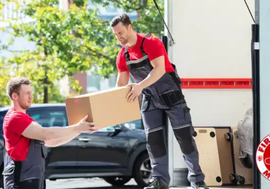 Two people carefully wrapping and packing items into moving boxes with Firehouse Movers.