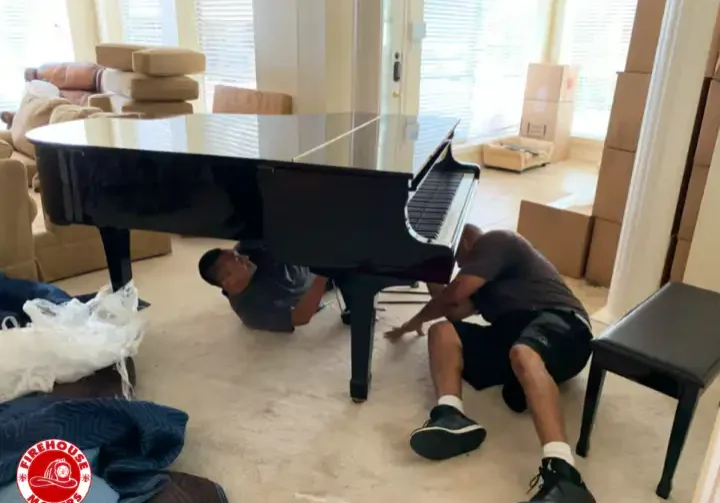 Professional movers from Firehouse Movers carefully wrapping and moving a upright piano.